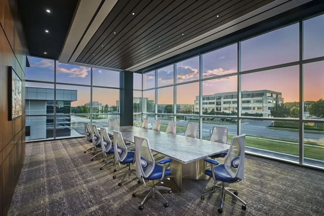 Corporate boardroom with floor-to-ceiling windows and custom wood millwork by Homestead Woodworks, featuring a large conference table and modern chairs